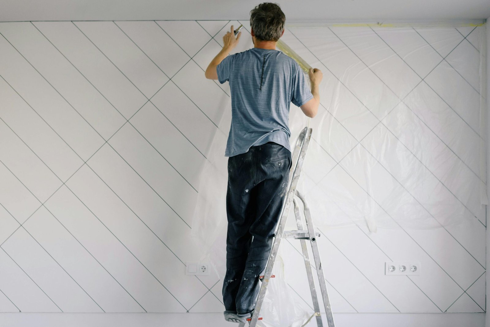 Adult man painting wall indoors during a home renovation project.